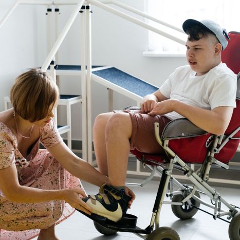 Someone with disabilities getting help putting their shoes on