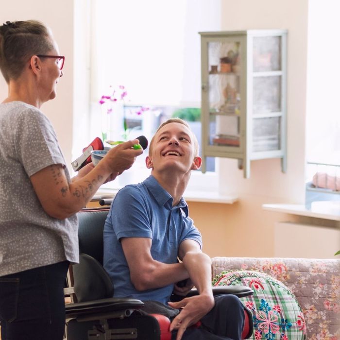 Adult with cerebral palsy smiling at their caretaker