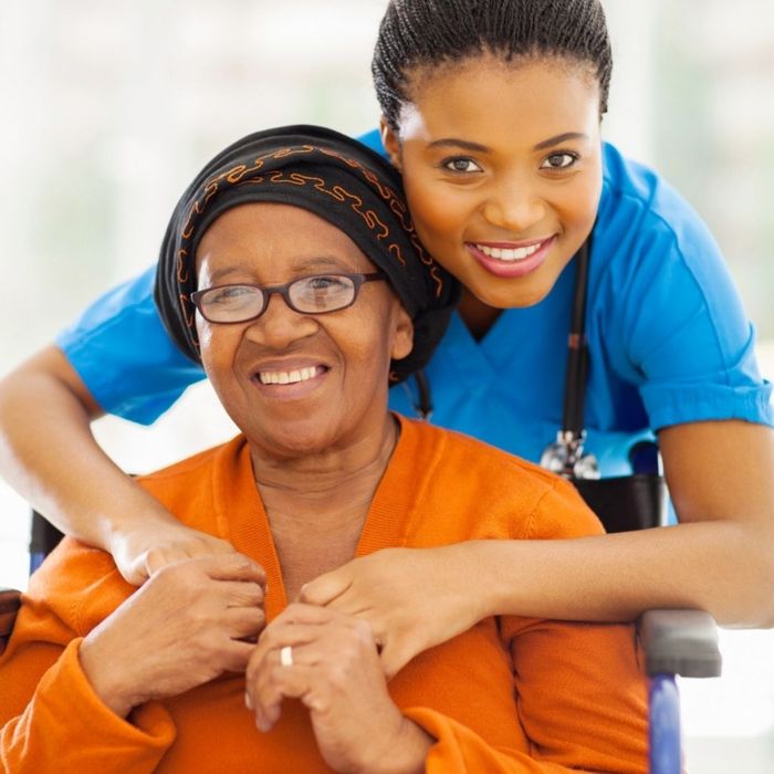 A caretaker and adult in a wheelchair smiling and posing